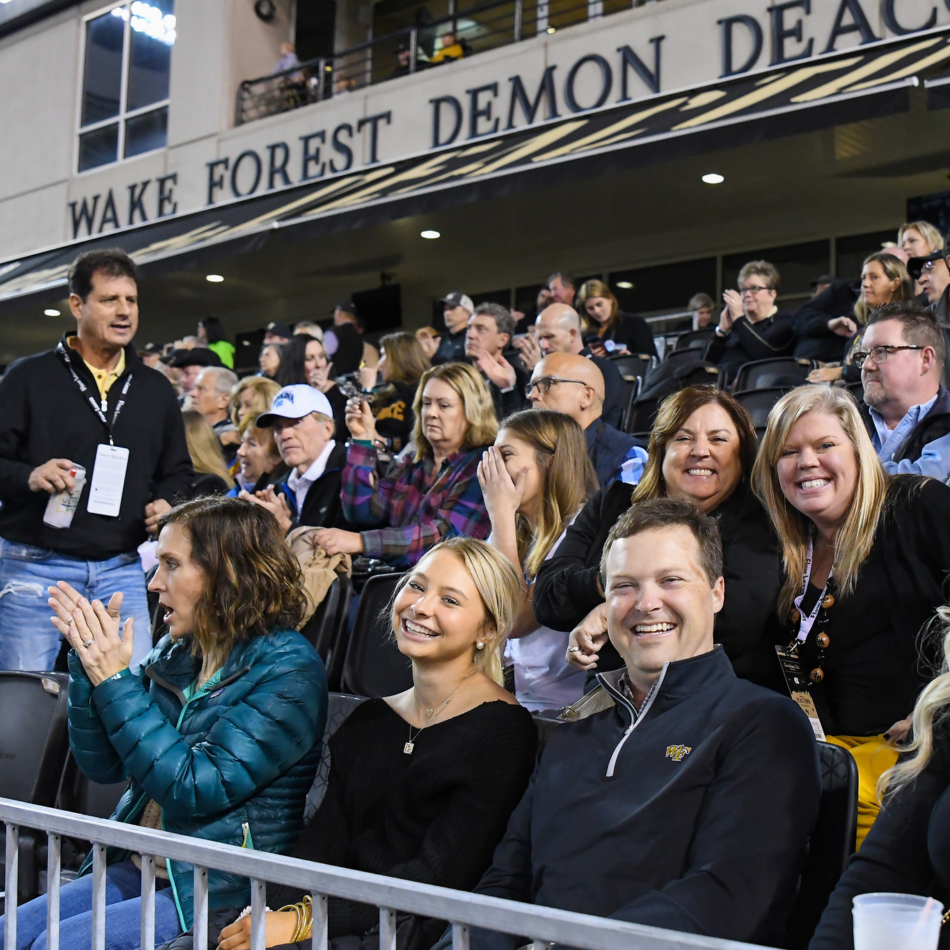 Photo of people smiling and posing for the camera in the outdoor seats of the Touchdown Club